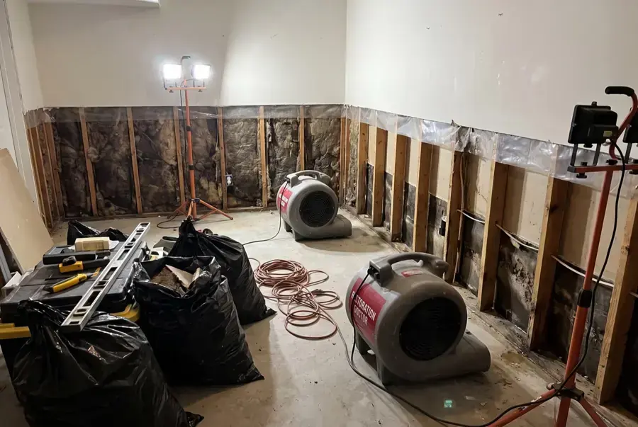 Red air movers drying a room with the lower drywall cut away in a Wilmington home