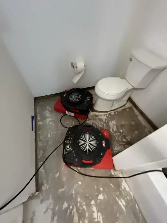 Air movers drying a bathroom floor with the flooring removed in Wilmington