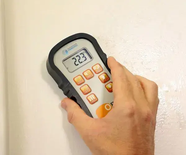 Moisture meter pressed against a wet wall during a Wilmington water damage inspection