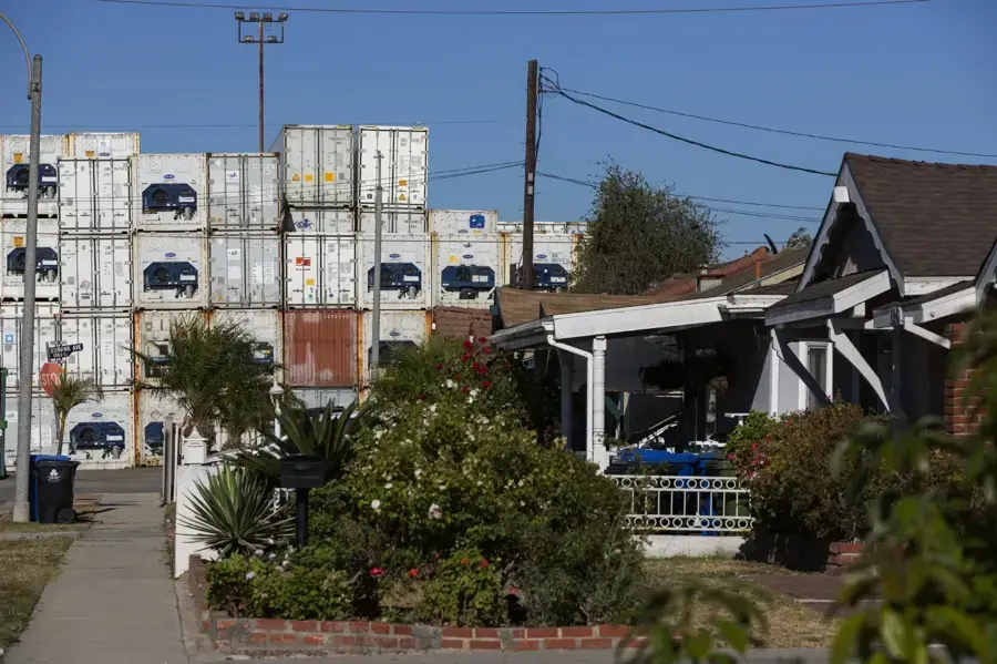 Older bungalow with stacked shipping containers behind it in the Wilmington harbor area