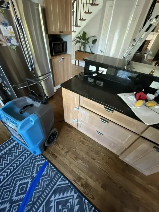 A dehumidifier with a drain hose drying a kitchen floor, shown for Carson water damage work